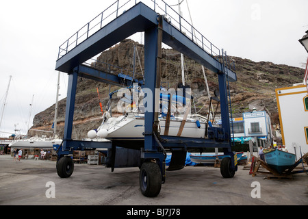 yacht being lifted out of the ocean by a mobile hoist in the marina of puerto de mogan gran canaria Stock Photo