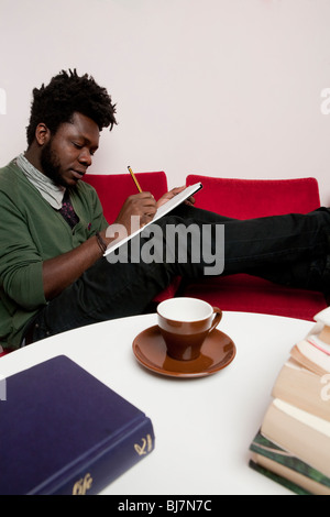 Man writing notes sitting on red sofa Stock Photo