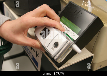 A mother pays for her family's groceries using the Edy-card wallet function of her mobile telephone, in a supermarket in Japan. Stock Photo