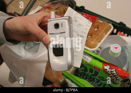 A mother pays for her family's groceries using the Edy-card wallet function of her mobile telephone, in a supermarket in Japan. Stock Photo