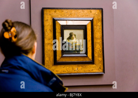 Woman tourist looking at The Lacemaker painting by Vermeer, Jan. The Louvre Museum, Paris. France. Stock Photo