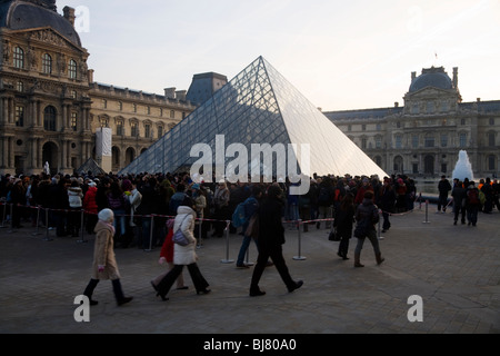 People queue at dawn for free entry to The Louvre Museum / Musee / Palais du Louvre, beside the Glass Pyramid. Paris, France. Stock Photo