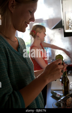 Two young women cooking together at home in the kitchen Stock Photo