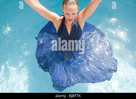 woman in blue polka dot dress dancing in swimming pool