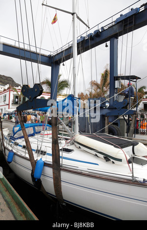 yacht being lifted out of the ocean by a mobile hoist in the marina of puerto de mogan gran canaria Stock Photo