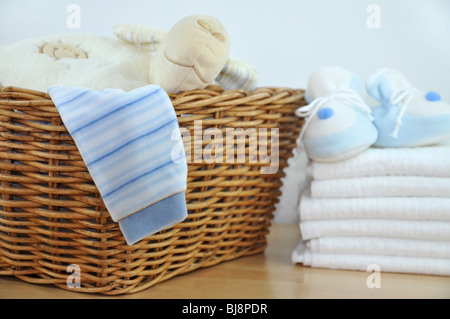 Laundry basket with blue clothes and slippers on a pile of diapers Stock Photo