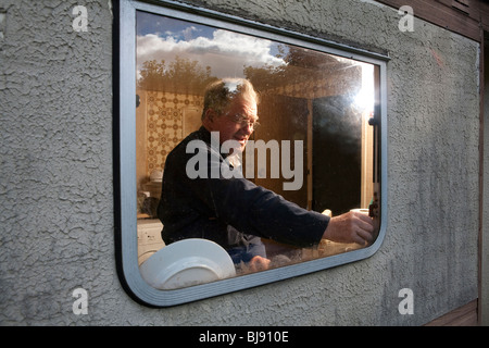 Senior man looking through the window of his motor home Stock Photo