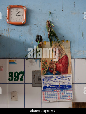 religious motif calendar on wall of butcher's market with clock Stock Photo
