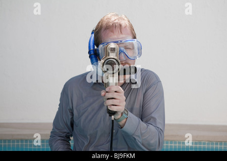 Man filming wearing clothes and goggles in swimming pool Stock Photo