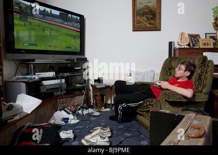 Boy playing videogame in cluttered living room Stock Photo