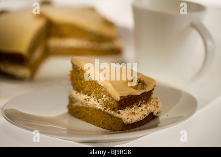 Slice of sponge cake decorated with butter cream icing and walnut on white plate Stock Photo