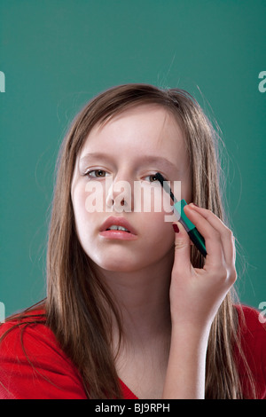 portrait of a pretty eleven years old girl putting on makeup Stock Photo