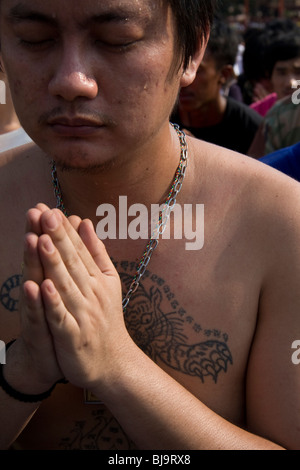 A man in prayer during Wai Kru Day at Wat Bang Phra, a Buddhist temple in Thailand where monks tattoo devotees. Stock Photo