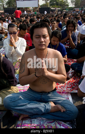 A young man in prayer during Wai Kru Day at Wat Bang Phra, a Buddhist temple in Thailand where monks tattoo devotees. Stock Photo