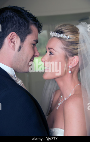Good looking bride and groom on their wedding day smiling and looking into each others eyes. Stock Photo