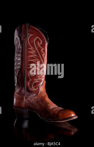 Vertical image of a brown leather cowboy boot on a reflective surface Stock Photo