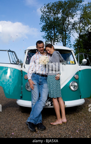 newly weds posing infront of their turquoise vw campervan before going on honeymoon Stock Photo