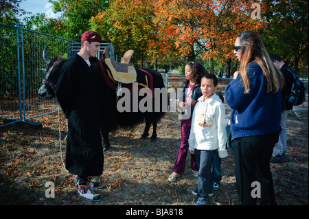 Paris, France - Young Family Talking to Male Teen Dressed in Tibetan Traditional Clothes, Holding Yak Bull,  Autumn. families in the park Stock Photo