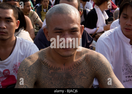 A young tattooed man at the Wat Bang Phra temple in Thailand, where monks tattoo their devotees with protective prayers. Stock Photo