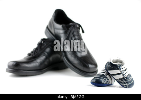 A pair of black man's shoes and a pair of blue baby shoes for the newborn. Father and son concept. Stock Photo