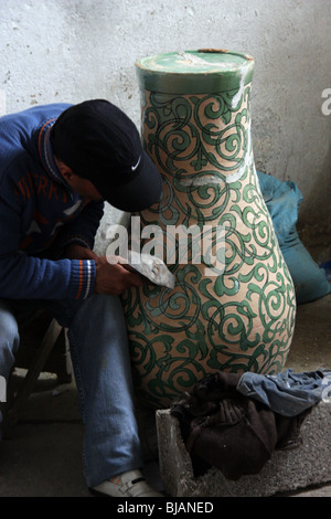 Man working on the decorations of a handmade vase at a tiles factory in Fez, Morocco Stock Photo