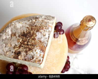 A celebration tower of whole round cheeses with a large wedge of blue cheese with a bottle of pink champagne Stock Photo