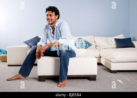 Young Hispanic man sitting at home alone on couch Stock Photo