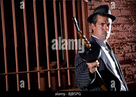 Gangster holding Tommy gun on lookout Stock Photo