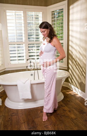 Pregnant woman standing in bathroom in pajamas Stock Photo