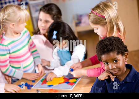 African-American boy in preschool, kids and teacher in background Stock Photo