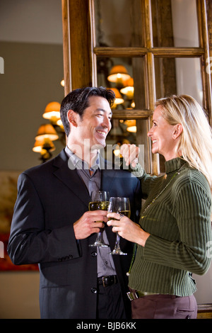 Affectionate mid-adult interracial couple drinking wine in elegant home Stock Photo