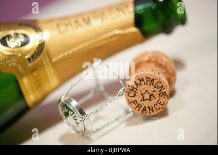 Closeup of champagne cork with out of focus opened bottle in the background Stock Photo