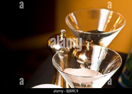 Salt and pepper displayed in open glasses, with metal pepper mils present. Stock Photo