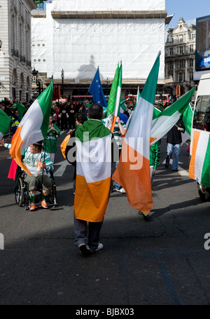 People carrying the Irish Tricolour during the St Patricks Day Parade in London. Stock Photo