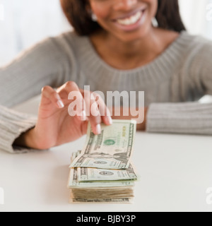 Mixed race woman taking money from stack Stock Photo