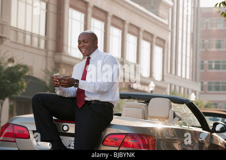 Black businessman text messaging on cell phone outdoors Stock Photo
