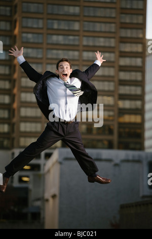 Excited mixed race businessman jumping in mid-air Stock Photo
