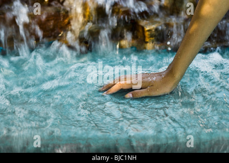 Water flowing from waterfall over woman's hand Stock Photo