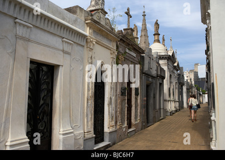 two female tourists walk past row of older mausoleums on a street in recoleta cemetery capital federal buenos aires Stock Photo