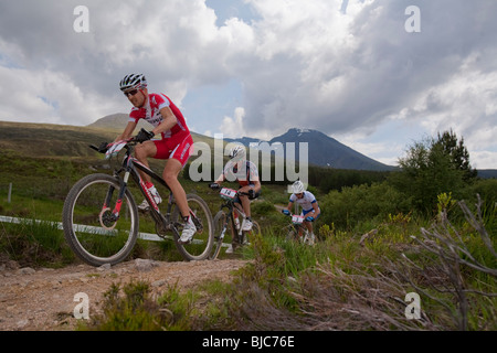 Mountain bikers climb a countryside trail during the UCI Mountain Bike World Cup in Fort William, Scotland. Stock Photo