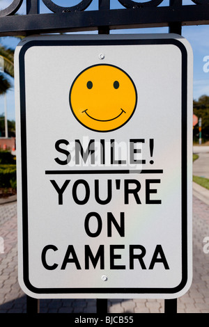 A Smile You're on Camera sign affixed to security gates Stock Photo