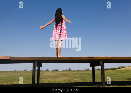 Woman standing on deck with arms out, rear view Stock Photo