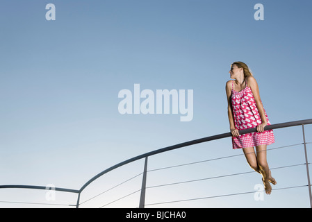 Woman holding on to railing, looking away, low angle view Stock Photo