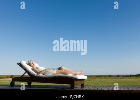 Woman napping on lounge chair on deck Stock Photo