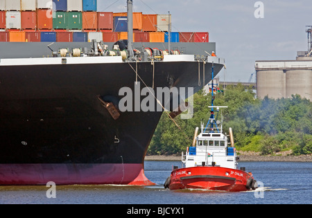 Container ship with tugboat in a harbor Stock Photo