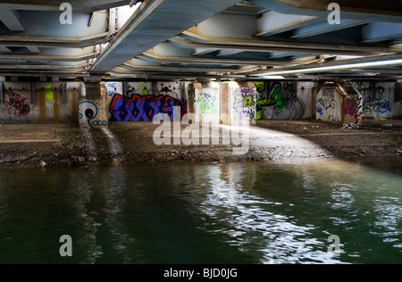 A scene of urban dereliction and decay with graffiti under the main railway passing over the Oxford canal Stock Photo