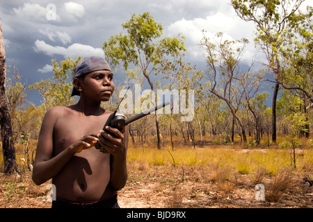 Aboriginal boy Mitchell using a stat phone as a storm approaches Gamedi outstation in ArnhemLand NT Australia Stock Photo