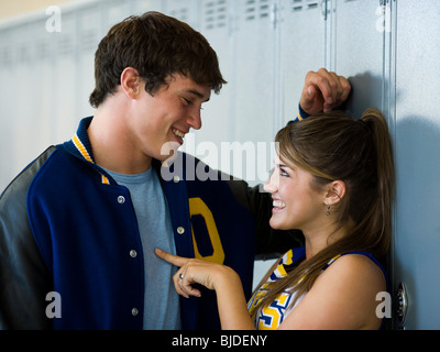Cheerleader and football player flirting in front of lockers. Stock Photo