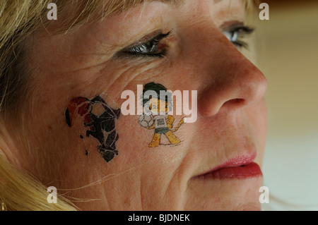 Female soccer supporter wearing a tattoo of Zakumi the host nations mascot and the FIFA logo 'Football is Life' emblem for World Stock Photo