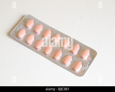 A blister pack of pink Statin tablets on a white background